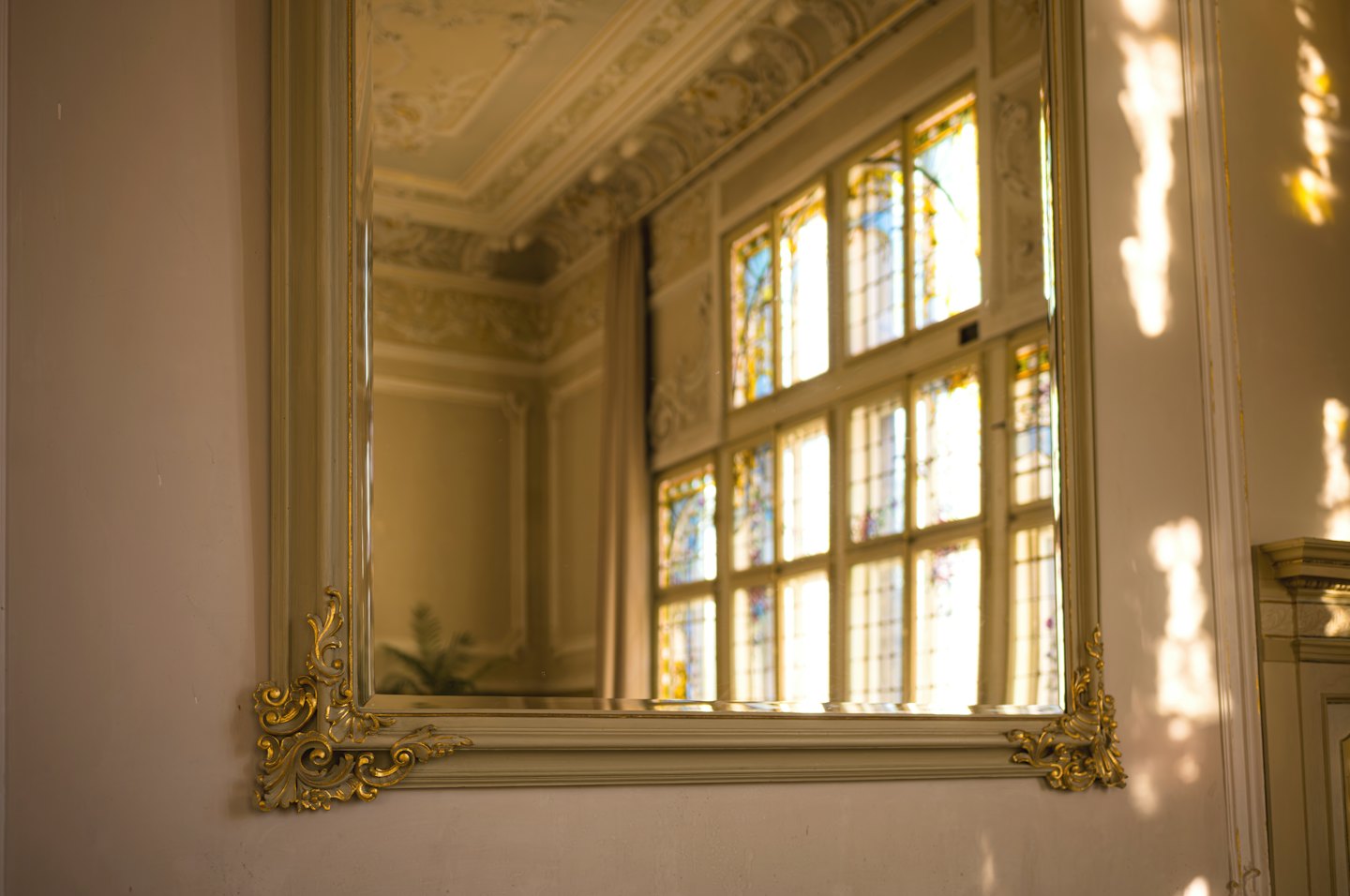 An ornate mirror with gold accents hangs on a wall.