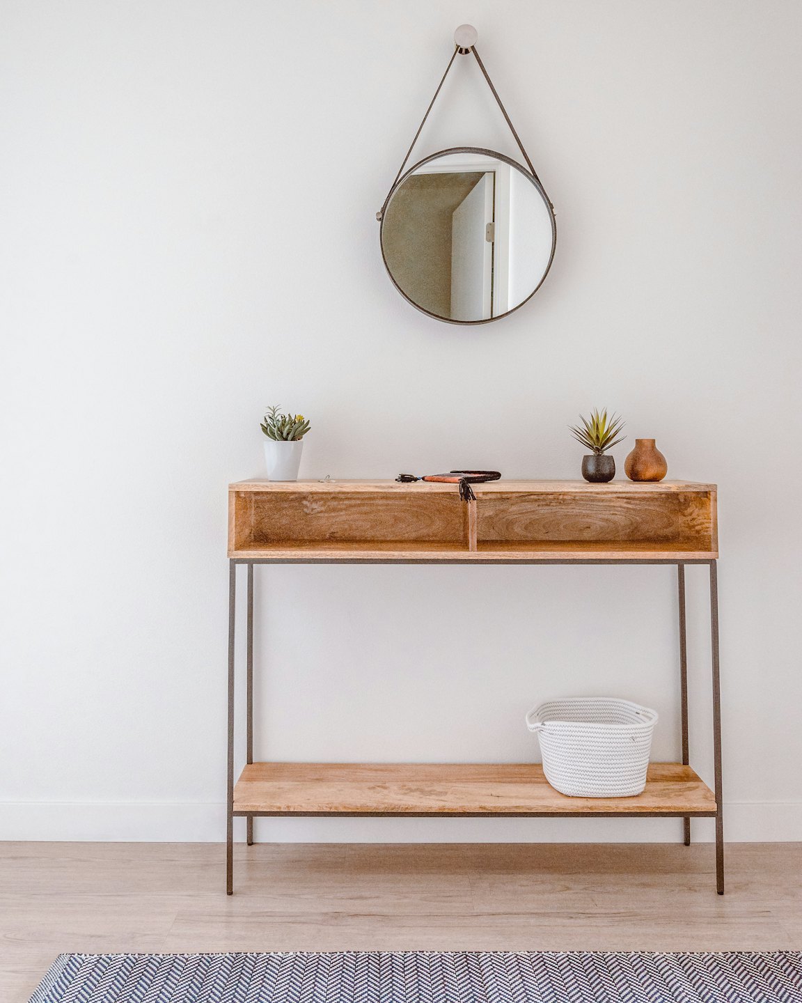Wooden console table with succulents and mirror in entryway.
